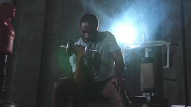 Beden eğitiminde spor. Spor salonunda dambılları toplayan Afrikalı Amerikalı bir vücut geliştirici. Fitness kulübünde halterli kasları çalıştırmak için ağırlık çalışıyorum. Spor yapan bir adam. Sağlıklı yaşam tarzı