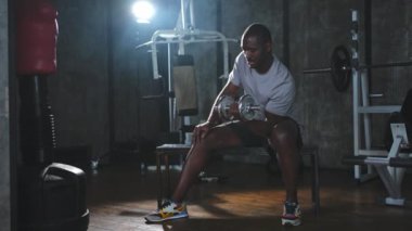 Beden eğitiminde spor. Spor salonunda dambılları toplayan Afrikalı Amerikalı bir vücut geliştirici. Fitness kulübünde halterli kasları çalıştırmak için ağırlık çalışıyorum. Spor yapan bir adam. Sağlıklı yaşam tarzı