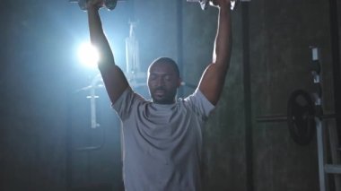 Beden eğitiminde spor. Spor salonunda dambılları toplayan Afrikalı Amerikalı bir vücut geliştirici. Fitness kulübünde halterli kasları çalıştırmak için ağırlık çalışıyorum. Spor yapan bir adam. Sağlıklı yaşam tarzı