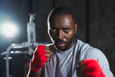 Spor salonunda boksör. Saldırgan Afrikalı dövüşçü boks eğitiminden sonra dinleniyor kameraya bakarak dövüşmeye hazır. Güçlü terli adam yumruklarını eğitiyor. Doğruca antrenmana hazırlanıyor.