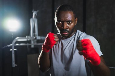 Spor salonunda boksör. Saldırgan Afrikalı dövüşçü boks eğitiminden sonra dinleniyor kameraya bakarak dövüşmeye hazır. Güçlü terli adam yumruklarını eğitiyor. Doğruca antrenmana hazırlanıyor.