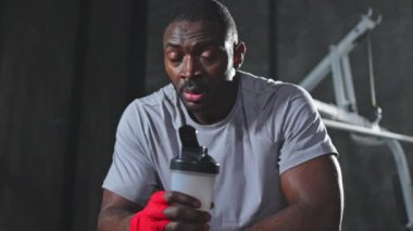 Spor salonunda boksör. Spor salonundaki boks antrenmanından sonra dinlenen kırmızı boks ambalajlı yorgun Afrikalı boksör. Boks müsabakasından sonra güçlü, terli bir sporcu. Spor salonunda antrenman günü