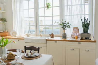 İskandinav klasiği beyaz ve ahşap çiçekli minimalist mutfak. Modern beyaz mutfak, çağdaş tarz iç tasarım. Boş parlak beyaz iç mekan, mutfak minimumu
