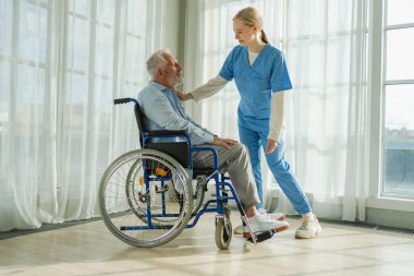 Emeklilik sağlık hizmetlerine destek ol. Hemşire tekerlekli sandalyedeki yaşlı adama yardım ediyor. Hasta ve kadın tıbbi bakım için huzurevinde. Engelli insanlar için tekerlekli sandalyede felçli bir adama bakan hemşire.