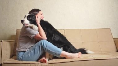 Gülümseyen kadın evdeki kanepede köpek yavrusu çoban köpeğiyle oynuyor. Sahibi kanepede oturan köpeği okşayan bir kız. Evcil hayvan sevgisi Dostluk Destek Takımı konsepti