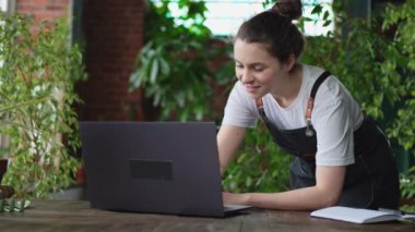 Botanik mağazasında çalışan çiçekçi kadın bahçıvan. İnternette müşteriyle iletişim kuran dizüstü bilgisayar siparişleri veren bitkiler kullanıyor. Çiçekçide çalışan küçük bir işletme sahibi. Kendi işini kur.