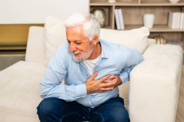 Kalp krizi, kalp krizi. Memnuniyetsiz orta yaşlı adam göğüs ağrısı çekiyor kalp krizi geçiriyor evde sağlık sorunları var. Yaşlı büyükbaba göğsüne dokunuyor ve damar tıkanıklığı yaşıyor.