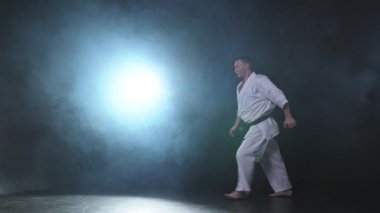 Siyah kuşak atlamalı, beyaz kimonolu, karate dövüş sanatları için güçlü bir dövüşçü. Adam eğitimi gölge dövüşü alıştırması yapıyor dövüş antrenmanlarına hazırlanıyor antrenmanlara hazır