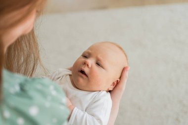 Evde mutlu bir aile. Anne elleri kucağında küçük bir kız çocuğu. Anne ve bebek evde birlikte oynayarak rahatlar. Anne bebeğe sevgiyle sarılır. Bebeği emziren anne.