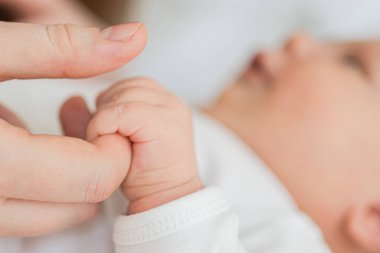 Mutlu bir aile. Yeni doğmuş küçük bir bebek, anne avucunun üzerinde küçük bir el. Yeni doğmuş bebek doğumdan sonra ebeveyn parmağı tutuyor. Anne bebek evde. Yeni hayatın korunmasını destekle. Dikkatli kullan.