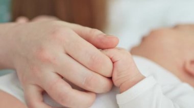 Mutlu bir aile. Yeni doğmuş küçük bir bebek, anne avucunun üzerinde küçük bir el. Yeni doğmuş bebek doğumdan sonra ebeveyn parmağı tutuyor. Anne bebek evde. Yeni hayatın korunmasını destekle. Dikkatli kullan.