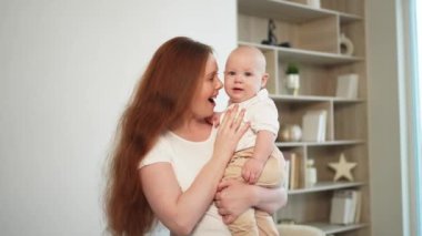 Evde mutlu bir aile. Anne kucağında küçük bir kız çocuğu. Anne ve bebek evde birlikte oynayarak rahatlar. Anne bebeğe sevgiyle sarılır. Bebeği emziren anne.