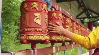 Seyyah kadın eli dokunarak Budist manastırında Budist dua çarkını çeviriyor. Budist taş tapınağında duacı çarkları var. Budizm dini kavramı