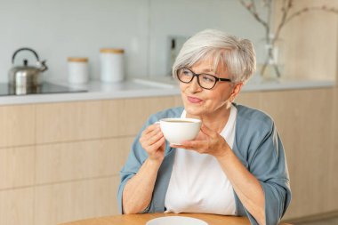 İyi sabahlar. Huzur, evde mutfakta sıcak çay içen yaşlı yaşlı yaşlı kadın büyükanneyi rahatlatıyor. Olgun bir kadın, modern bir evde tek başına sakin bir sabah geçirir. Emeklilik konsepti
