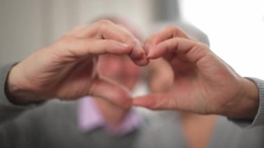 Aşk, barışı şekillendirir. Yaşlı çift elleriyle kalp şekli yaratıyor. Yetişkin, olgun koca eşi kalp işareti gösteriyor. Mutlu emekliler ailesi. Seni seviyorum Sevgililer Günü 'n kutlu olsun