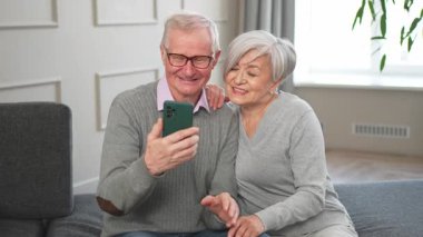 Görüntülü arama. Akıllı telefonlu mutlu son sınıf kadın erkek video görüşmesi yapıyor. Olgun yaşlı büyükbaba internette konuşuyor. Eski nesil modern teknoloji kullanımı. Sanal toplantı çevrimiçi sohbet