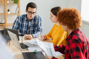 Takım çalışması beyin fırtınası. Çeşitli meslektaşlar birlikte çalışarak mali istatistikleri tartışırlar. Bir grup mutlu modern insan yaratıcı ofiste oturmuş iş tartışıyorlar. Genç profesyonel takım