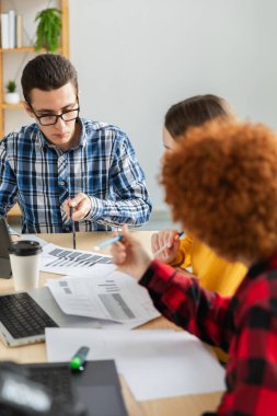 Takım çalışması beyin fırtınası. Çeşitli meslektaşlar birlikte çalışarak mali istatistikleri tartışırlar. Bir grup mutlu modern insan yaratıcı ofiste oturmuş iş tartışıyorlar. Genç profesyonel takım