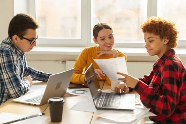 Takım çalışması beyin fırtınası. Çeşitli meslektaşlar birlikte çalışarak mali istatistikleri tartışırlar. Bir grup mutlu modern insan yaratıcı ofiste oturmuş iş tartışıyorlar. Genç profesyonel takım