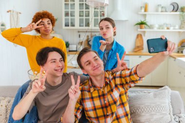 Keyfinize bakın. Mutlu arkadaş grubu selfie çekiyor. Partide arkadaşlarının fotoğrafını çeken bir adam. Telefonda fotoğraf çeken bir grup çok ırklı genç. Gençler gülümsemenin keyfini çıkarırlar.