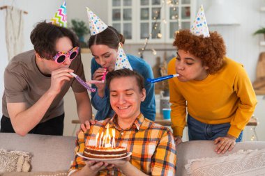 Bir dilek tut. Parti şapkası takmış bir adam doğum günü pastasında yanan mumları üflüyor. Doğum günün kutlu olsun. Arkadaş grubu adama mutlu yıllar diliyor. İnsanlar doğum gününü evde partiyle kutluyor.