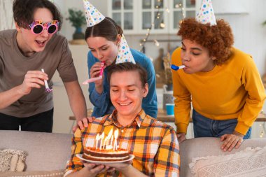 Bir dilek tut. Parti şapkası takmış bir adam doğum günü pastasında yanan mumları üflüyor. Doğum günün kutlu olsun. Arkadaş grubu adama mutlu yıllar diliyor. İnsanlar doğum gününü evde partiyle kutluyor.