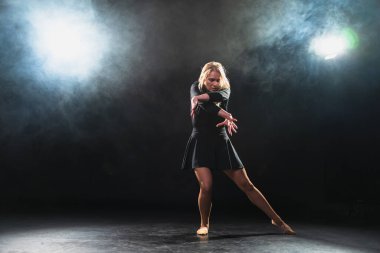 Siyah arka planda dumanla poz veren çağdaş kadın dansçı. Yetişkin kadın sanatçı ifade ile dans ediyor. Modern balerin karanlıkta dans ediyor. Tutku karanlıkta dans eder. Esneklik dengesi