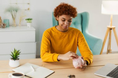 Gelecek için para yatırımı biriktiriyorum. Afrika kökenli Amerikalı bir kız pembe domuz kumbarası tutuyor ve para koyuyor. Yatırım bütçesi tasarrufu iş zenginliği emeklilik finansal para bankacılık kavramı