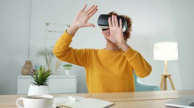 Evde sanal gerçeklik metavers VR gözlüğü takan Afro-Amerikalı genç bir kadın. Sanal gerçeklik kaskındaki sanal gerçeklik deneyimi sırasında havaya dokunan kız. Yüksek teknolojili simülasyon video oyunu kavramı