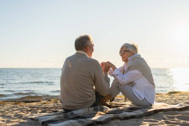 Sahilde oturmuş el ele tutuşan olgun bir çift dışarıda eğleniyor. Yaşlı karı şefkatle el ele tutuşuyor. Büyükannem ve büyükbabam birlikte. Aile âşkı