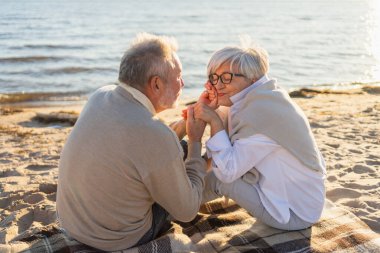 Sahilde oturmuş el ele tutuşan olgun bir çift dışarıda eğleniyor. Yaşlı karı şefkatle el ele tutuşuyor. Büyükannem ve büyükbabam birlikte. Aile âşkı
