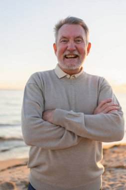 Sahilde kendine güveni tam orta yaşlı bir Avrupalı 'nın açık hava portresi. Yaşlı, olgun bir adam gülümsüyor. Mutlu büyükbaba kameraya bakıyor. Yüz portresi yakın çekim. Mutlu insanlar.