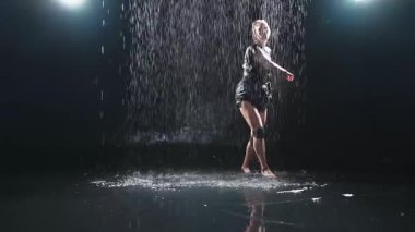 Siyah arka planda yağmur suyunda poz veren çağdaş kadın dansçı. Dişi sanatçı ifade ile dans ediyor. Modern balerin karanlıkta dans ediyor. Tutku karanlıkta dans eder. Esneklik dengesi