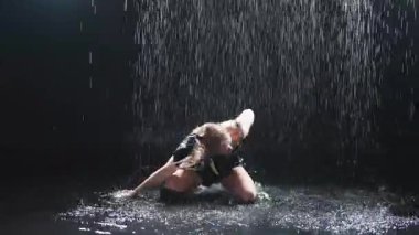 Siyah arka planda yağmur suyunda poz veren çağdaş kadın dansçı. Dişi sanatçı ifade ile dans ediyor. Modern balerin karanlıkta dans ediyor. Tutku karanlıkta dans eder. Esneklik dengesi