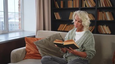 Huzur, evde kitap okuyan yaşlı ve yaşlı bir kadın. Olgun bir kadın dinleniyor. Evde tek başına sakin bir gün geçiriyor. Yetişkin kadın boş zamanlarını kitap okuyarak geçiriyor. Emeklilik konsepti