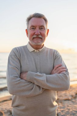 Sahilde kendine güveni tam orta yaşlı bir Avrupalı 'nın açık hava portresi. Yaşlı, olgun bir adam gülümsüyor. Mutlu büyükbaba kameraya bakıyor. Yüz portresi yakın çekim. Mutlu insanlar.