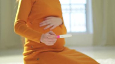 Pozitif hamilelik testi tutan kadın eli. Koca göbekli hamile bir kadın doğurganlık tedavisi görüyor ve tüp bebek bekliyor. Hamile annelik, gelecekteki annelik, ebeveynlik, yeni hayat.