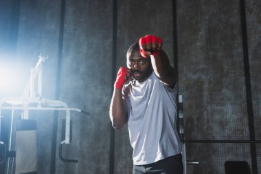 Beden eğitiminde. Afrikalı dövüşçü boksörlere yumruk atmaya hazır koruyucu bandajları kameraya sarar. Güçlü bir adam boks antrenmanına hazırlanıyor.