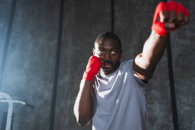 Beden eğitiminde. Afrikalı dövüşçü boksörlere yumruk atmaya hazır koruyucu bandajları kameraya sarar. Güçlü bir adam boks antrenmanına hazırlanıyor.