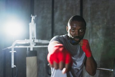 Beden eğitiminde. Afrikalı dövüşçü boksörlere yumruk atmaya hazır koruyucu bandajları kameraya sarar. Güçlü bir adam boks antrenmanına hazırlanıyor.