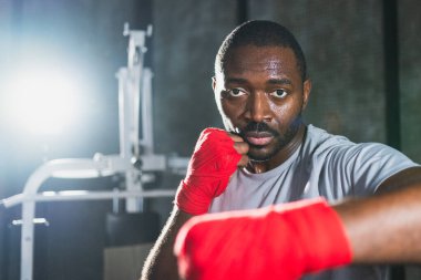 Beden eğitiminde. Afrikalı dövüşçü boksörlere yumruk atmaya hazır koruyucu bandajları kameraya sarar. Güçlü bir adam boks antrenmanına hazırlanıyor.