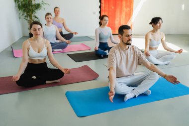 Yoga farkındalığı meditasyonu. Yoga sağlık farkındalığı meditasyonu için stüdyoda egzersiz yapan bir grup sporcu. Nilüfer çiçeğinde oturup yoga yapan erkek kadınlar meditasyon yapıyor.