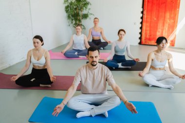 Yoga farkındalığı meditasyonu. Yoga sağlık farkındalığı meditasyonu için stüdyoda egzersiz yapan bir grup sporcu. Nilüfer çiçeğinde oturup yoga yapan erkek kadınlar meditasyon yapıyor.