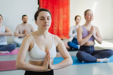 Yoga farkındalığı meditasyonu. Yoga sağlık farkındalığı meditasyonu için stüdyoda egzersiz yapan bir grup sporcu. Nilüfer çiçeğinde oturup yoga yapan erkek kadınlar meditasyon yapıyor.