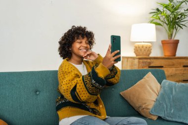 African American girl holding smartphone having video chat. Female blogger chatting with best friends in social network. Young woman having virtual meeting online chat video call at home