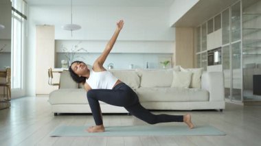 Yoga fitness antrenmanı. Sağlıklı Afrikalı kız evde yoga yapıyor. Pilates antrenmanı yapan bir kadın, yoga minderiyle spor yapıyor. Kız kilo vermek için antrenman yapıyor. Spor uygunluğu