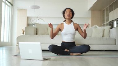 Yoga farkındalığı meditasyonu çevrimiçi. Afrikalı kadın evdeki bilgisayarında online derslerle yoga yapıyor. Lotus 'ta oturan kadın meditasyon yapıyor. Nefes egzersizi yapan bir kız. Evde yoga.