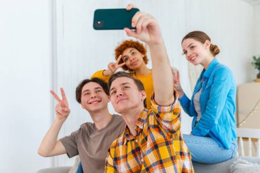 Keyfinize bakın. Mutlu arkadaş grubu selfie çekiyor. Partide arkadaşlarının fotoğrafını çeken bir adam. Telefonda fotoğraf çeken bir grup çok ırklı genç. Gençler gülümsemenin keyfini çıkarırlar.
