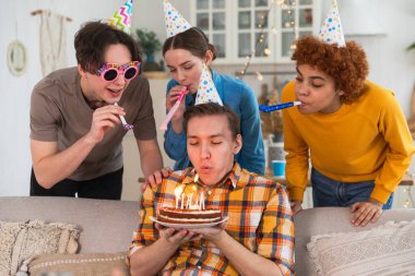 Bir dilek tut. Parti şapkası takmış bir adam doğum günü pastasında yanan mumları üflüyor. Doğum günün kutlu olsun. Arkadaş grubu adama mutlu yıllar diliyor. İnsanlar doğum gününü evde partiyle kutluyor.