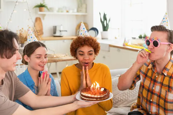 Bir dilek tut. Parti şapkası takan bir kadın doğum günü pastasında yanan mumları üflüyor. Doğum günün kutlu olsun. Bir grup arkadaş kızın doğum gününü kutluyor. İnsanlar doğum gününü evde partiyle kutluyor.
